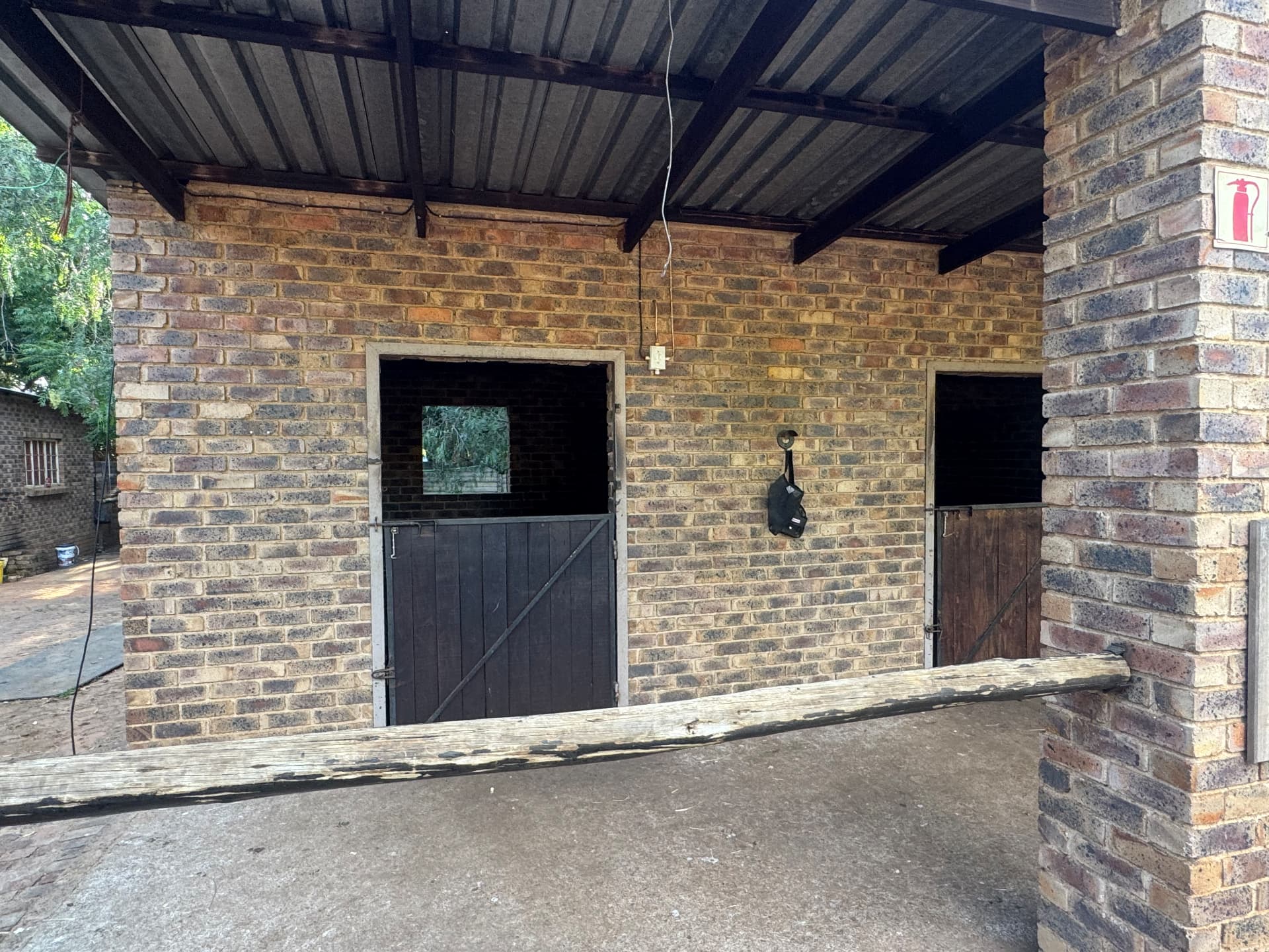Brick stables with wooden half-doors under a covered walkway